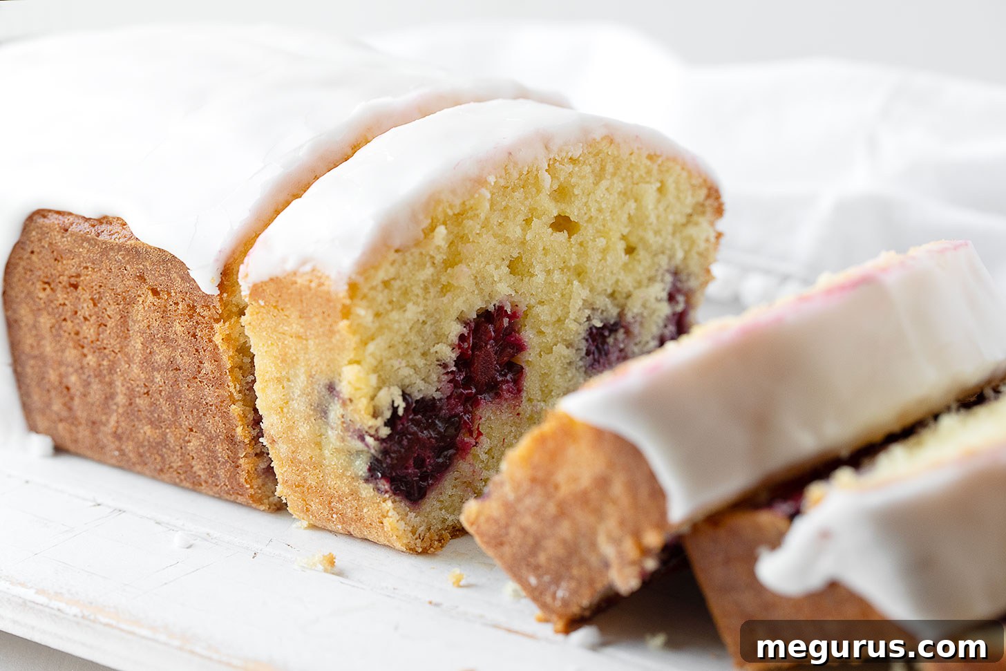 Lemon blackberry loaf sliced on cutting board.