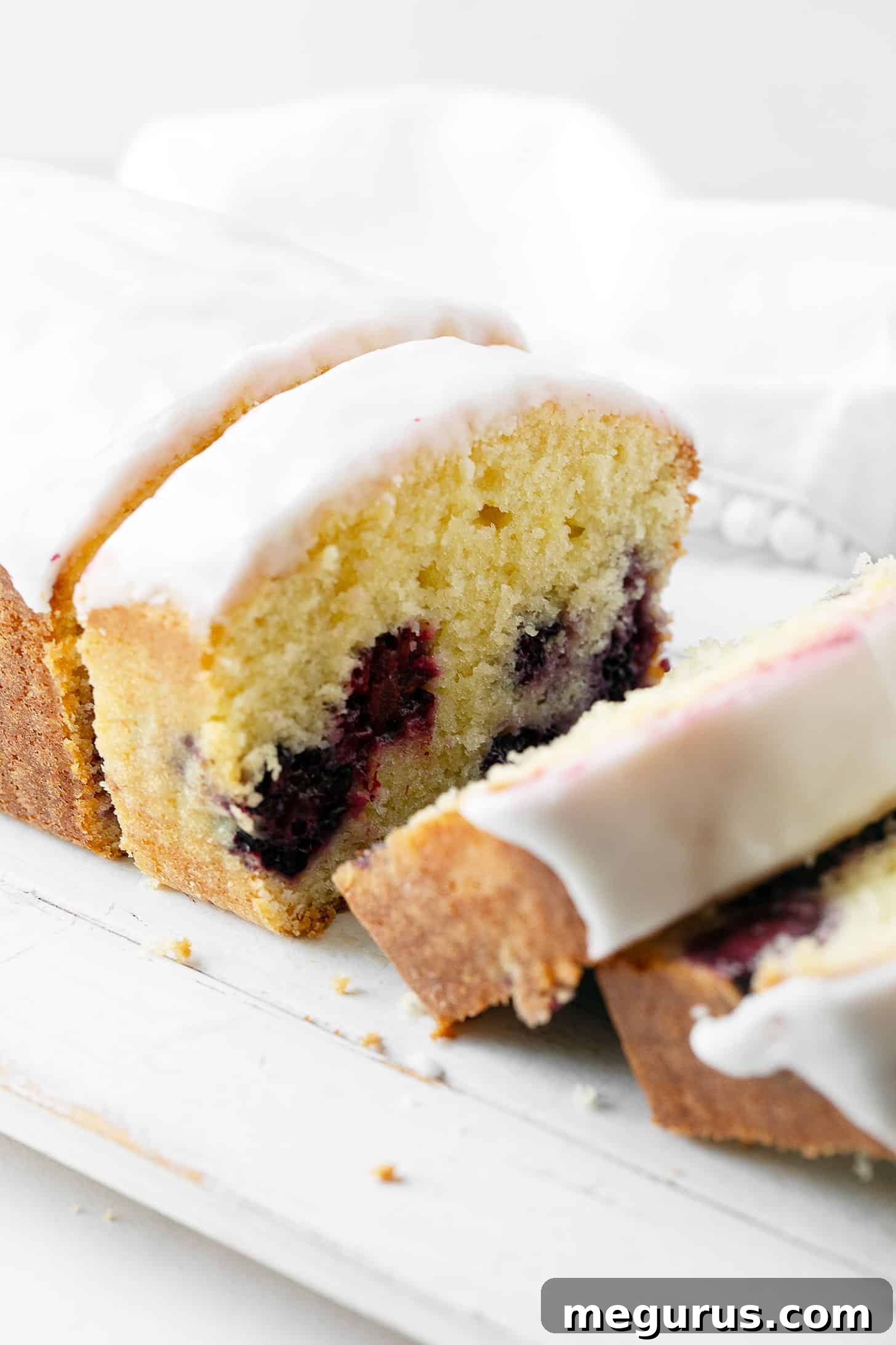 Lemon blackberry loaf sliced on a cutting board.