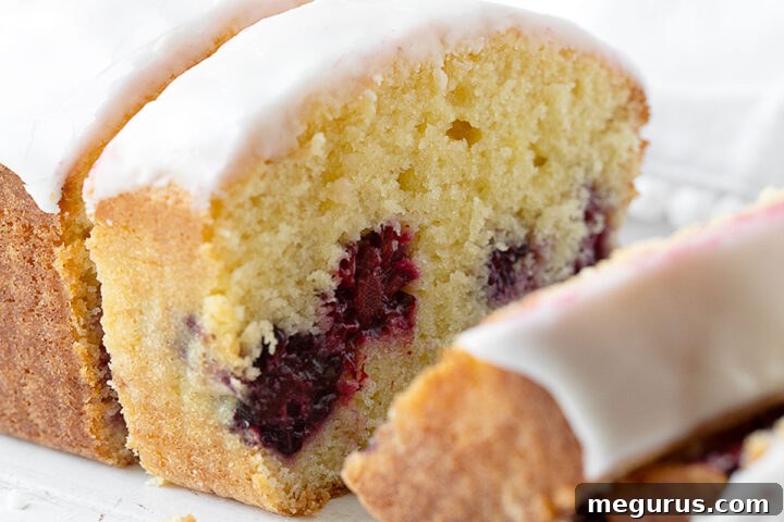 Lemon blackberry loaf sliced on cutting board.