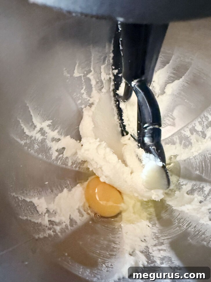 Adding an egg to the creamed butter and sugar.