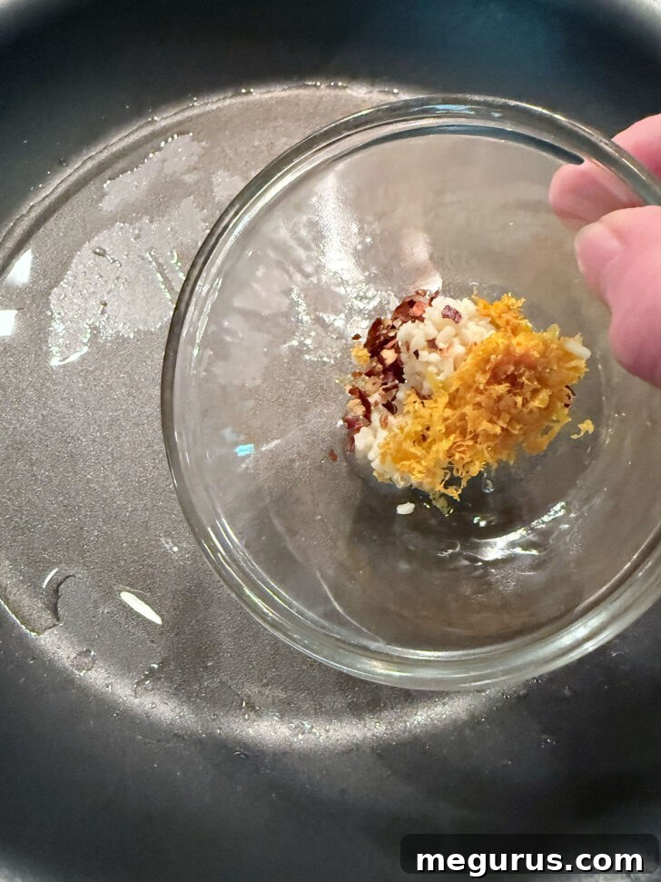 Adding orange zest and spices to a hot skillet.