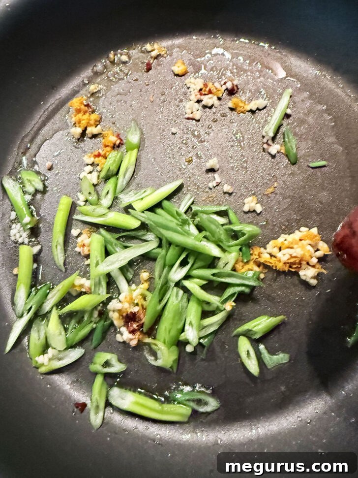 Adding some green onion to the skillet.