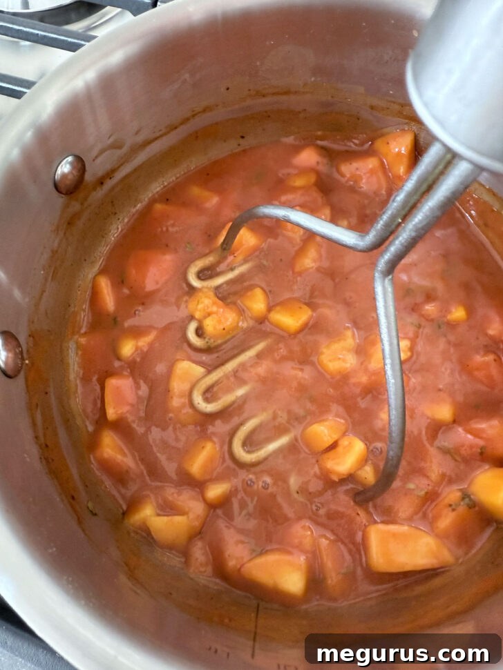 Breaking up the peaches with a potato masher during cooking.