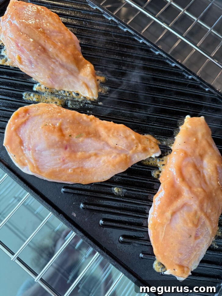 Sauce being brushed on chicken on a grill pan.