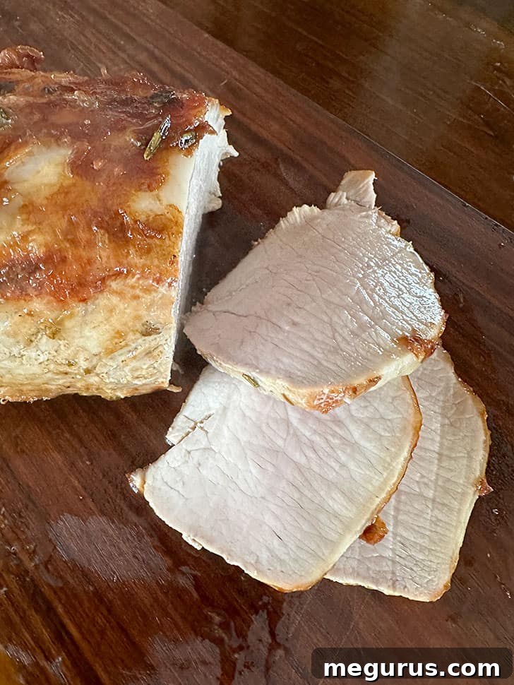 Thinly slicing the perfectly cooked and rested pork loin before serving with gravy.
