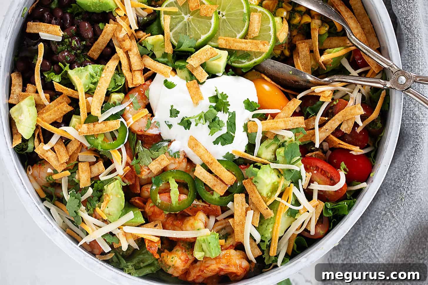 Shrimp taco salad in salad bowl with tongs.