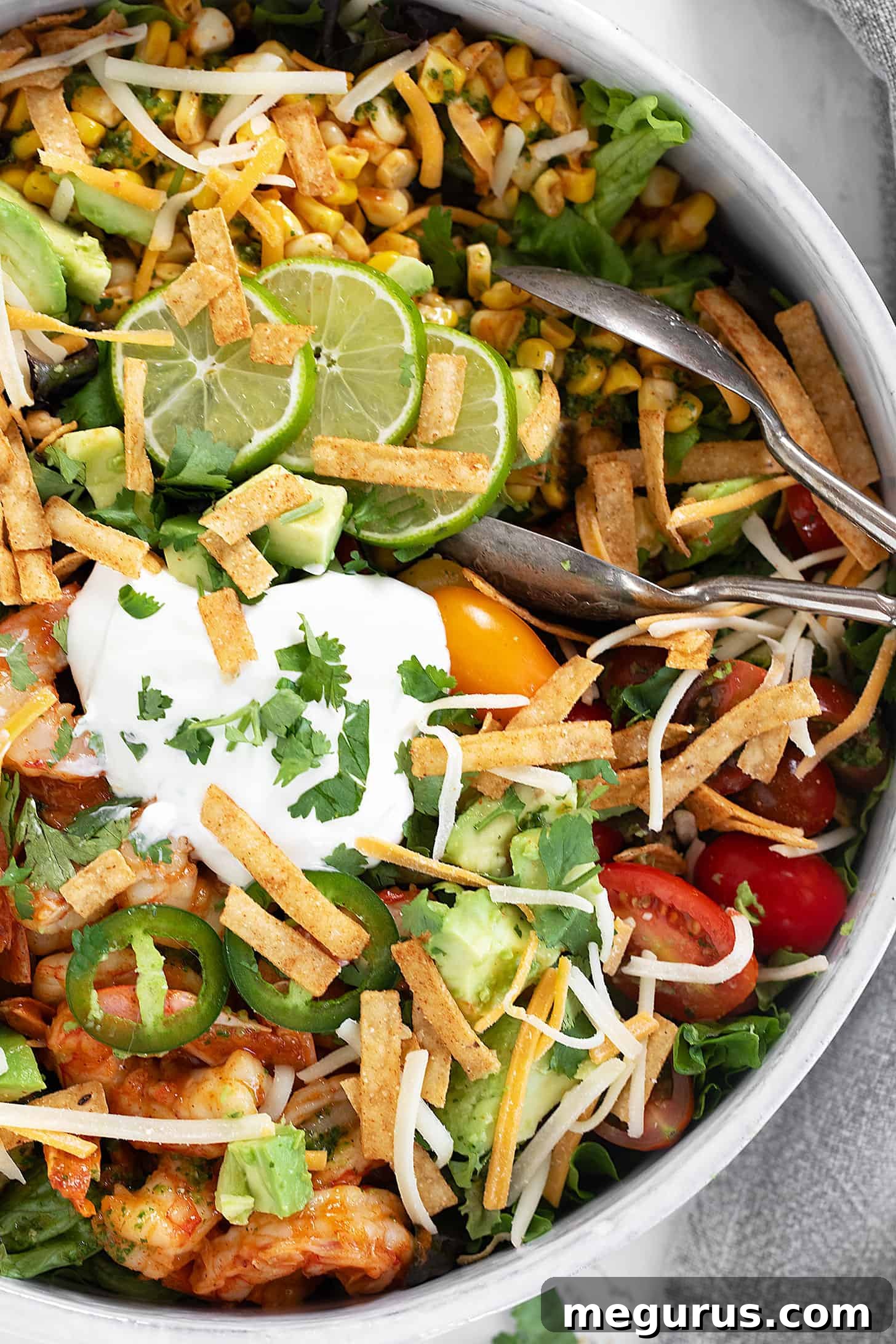 Shrimp taco salad in salad bowl with tongs.