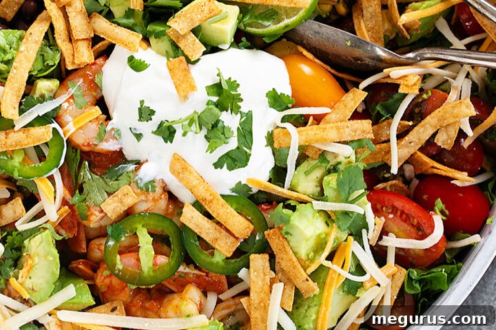 Shrimp taco salad in salad bowl with tongs.