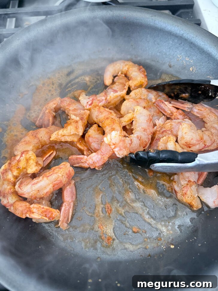 Sautéeing shrimp with taco seasoning in a skillet.