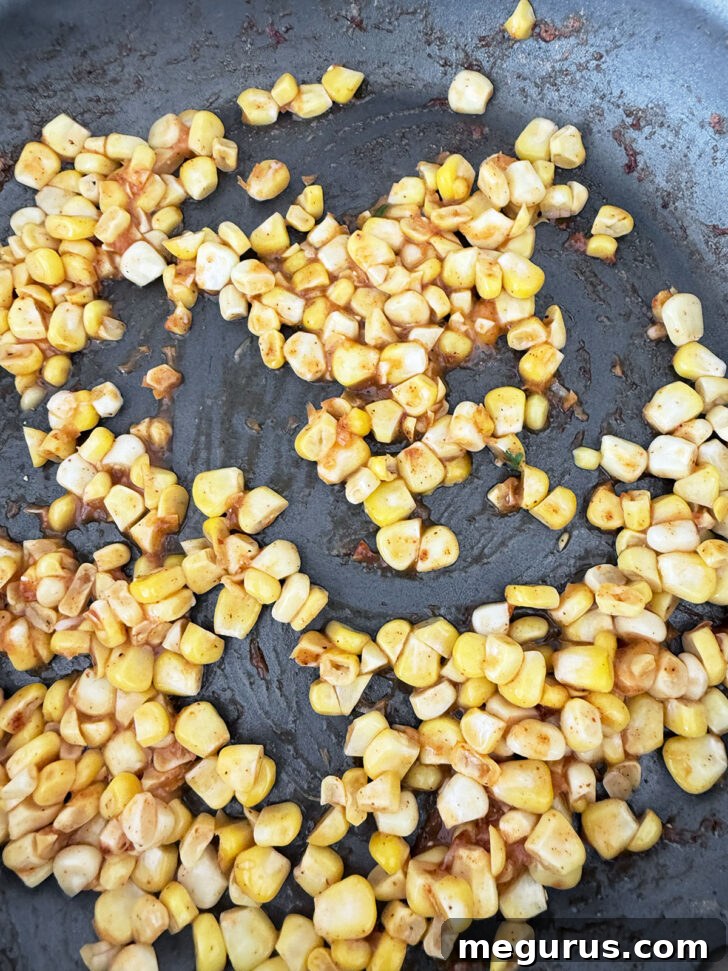 Sautéeing corn with taco seasoning in a skillet.