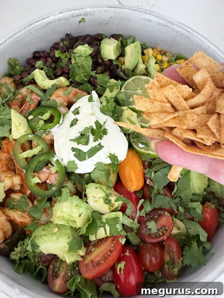 Sprinkling tortilla strips over the salad.