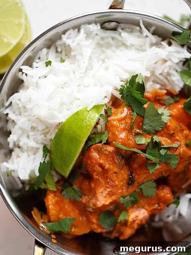 Shrimp tikka masala in copper bowls with rice, garnished with fresh cilantro.