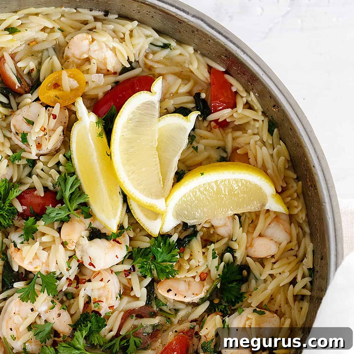 One-pan orzo with shrimp, spinach, and cherry tomatoes in a skillet.