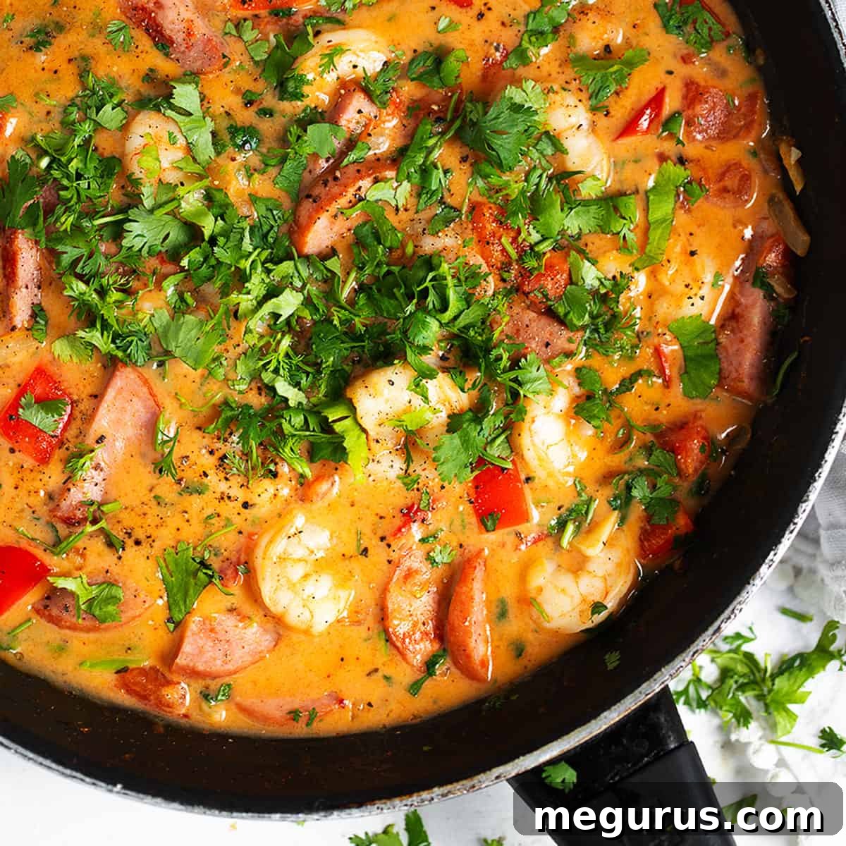 Cajun shrimp and sausage simmering in a cast iron skillet.