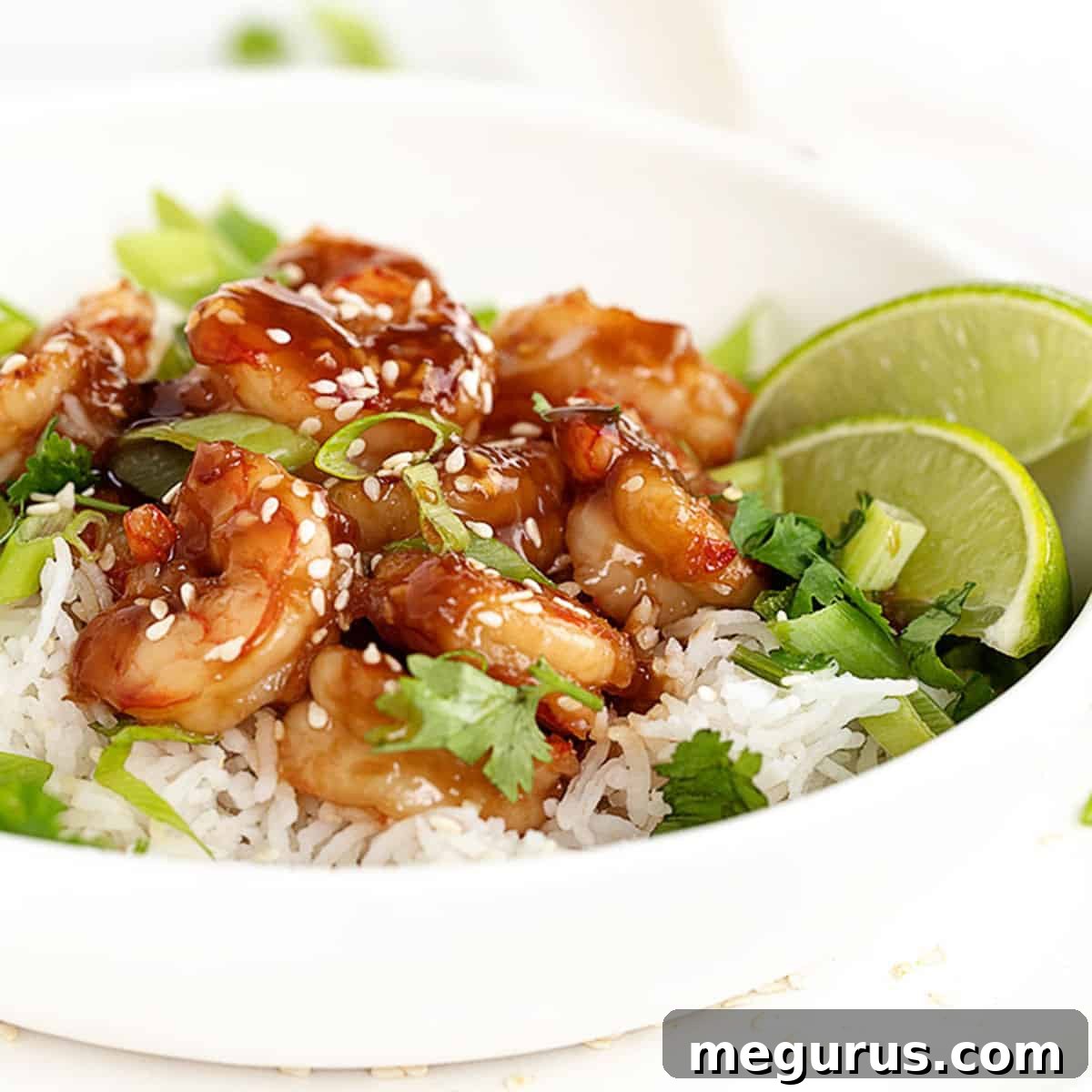 Honey garlic shrimp served in a bowl with white rice and green onions.