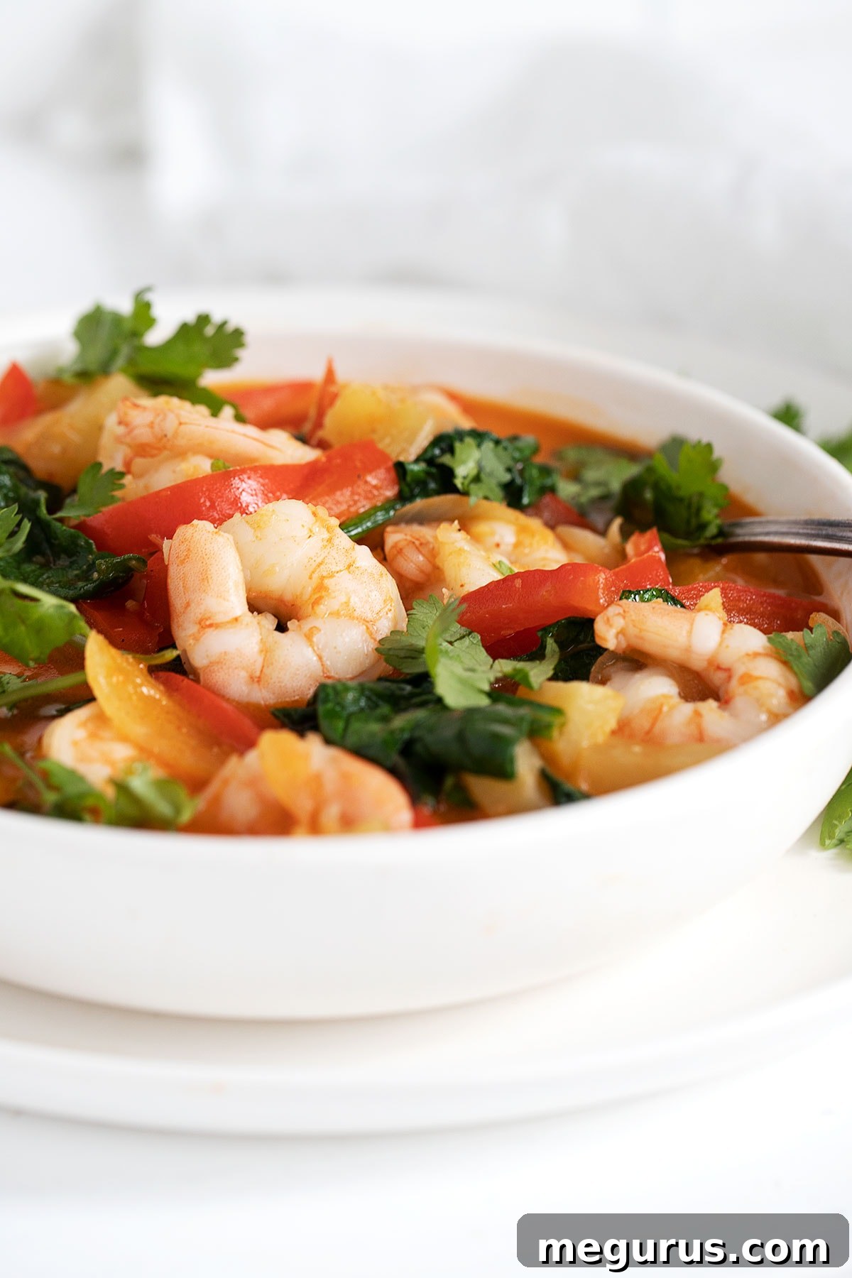 Thai red curry shrimp in a white bowl, ready to be served.