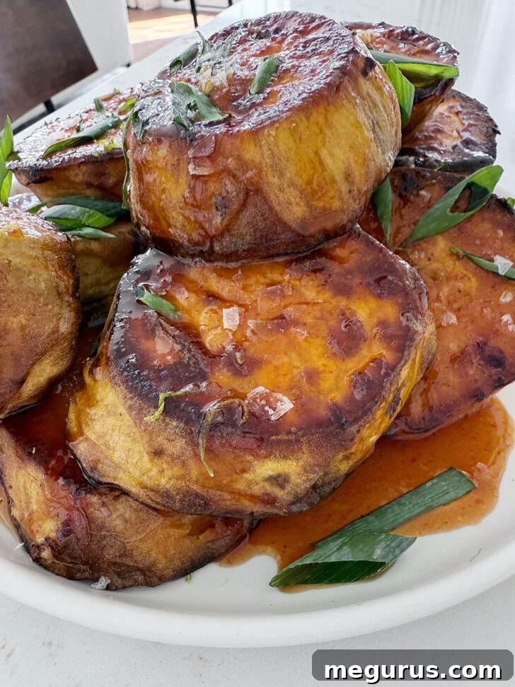 Plated honey sriracha melting sweet potatoes, garnished with diagonally sliced green onions and a sprinkle of flaky salt.