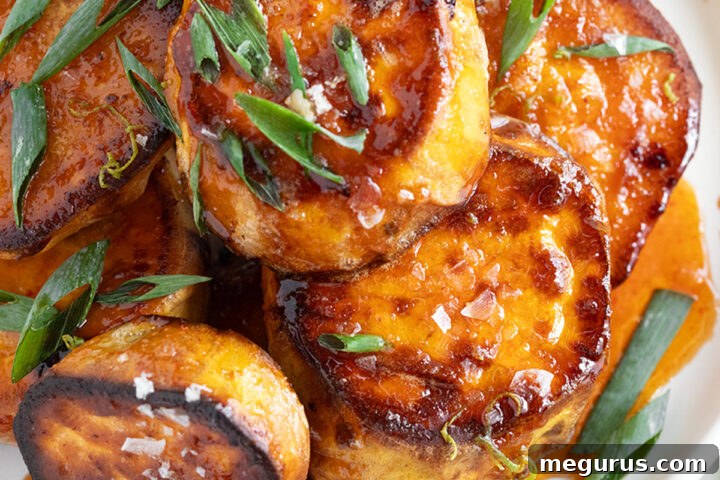 Melting sweet potatoes on a plate with a honey sriracha sauce.