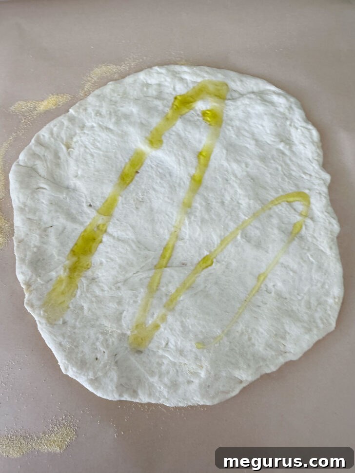 Pizza dough formed into a round and drizzled with olive oil.