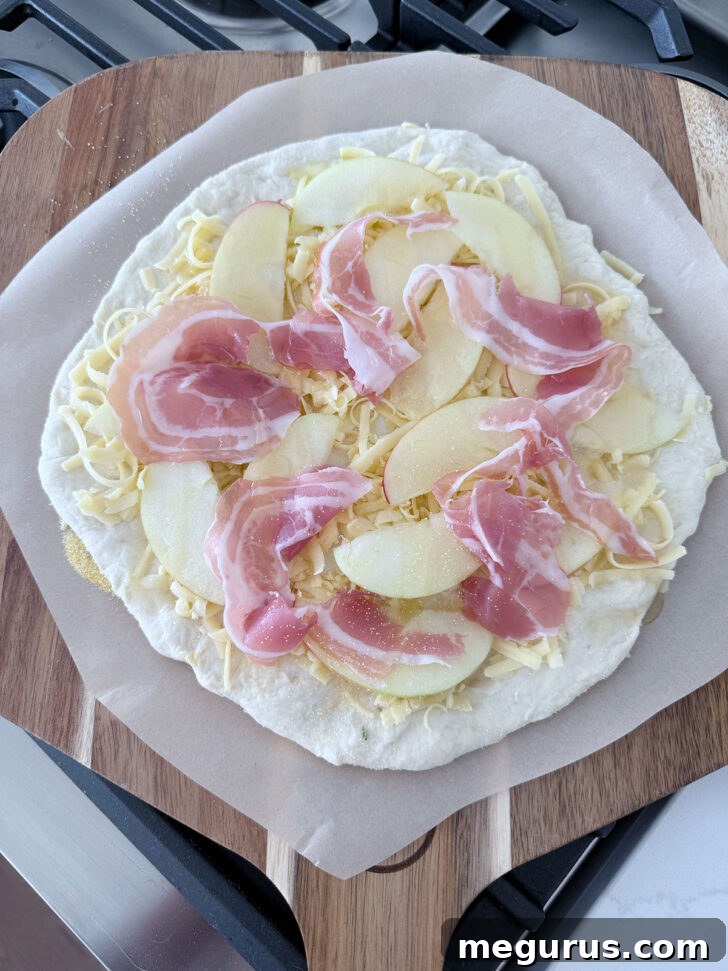 Apple cheddar pizza on pizza peel ready to go into the oven.