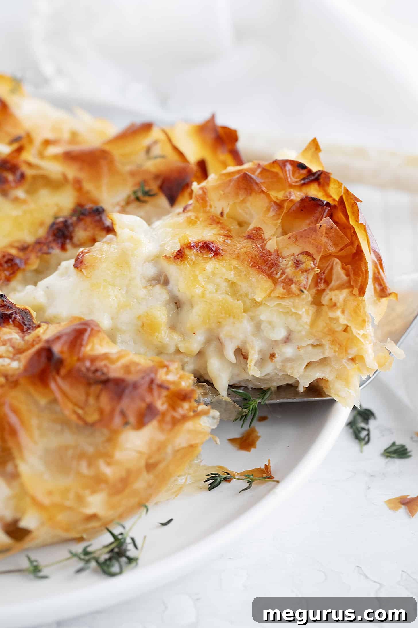 Another view of the sliced Cauliflower and Cheese Phyllo Pie on a white serving plate, showing the flaky crust and rich filling.