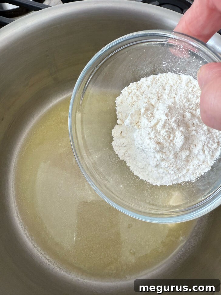 Flour being added to melted butter in a saucepan, the start of the cheese sauce.