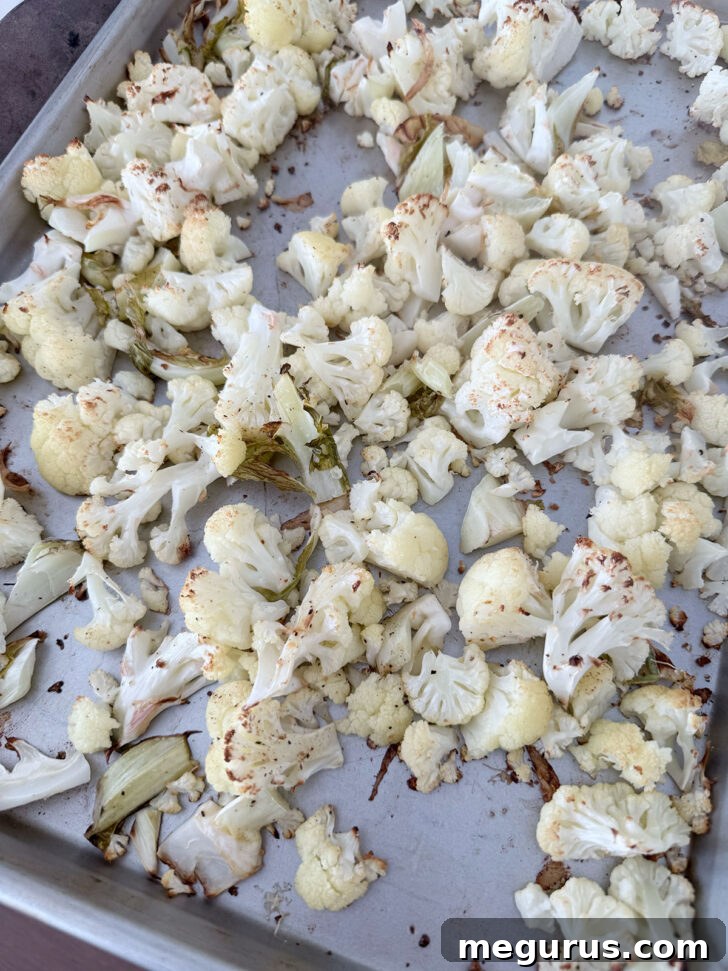 Perfectly roasted cauliflower on a baking sheet, slightly golden and tender.