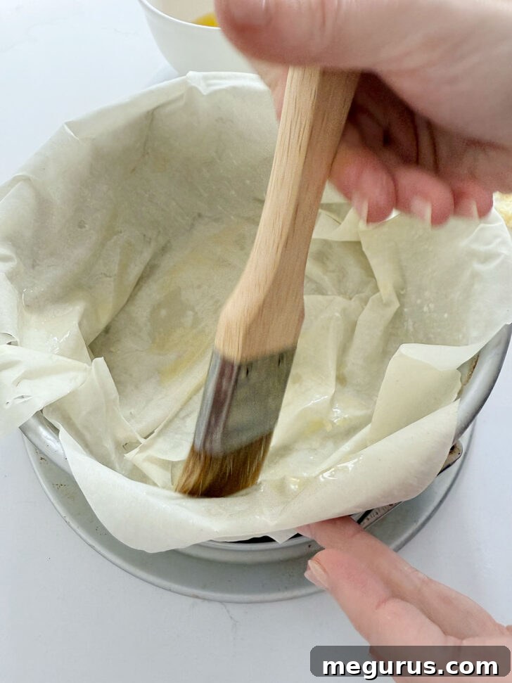 Layering phyllo sheets into a springform pan, generously brushing with melted butter between layers.