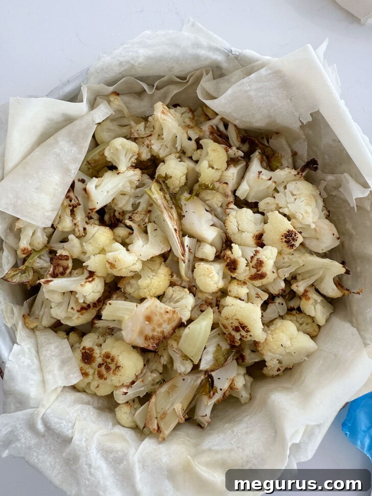 Roasted cauliflower being spooned into the phyllo-lined pan.