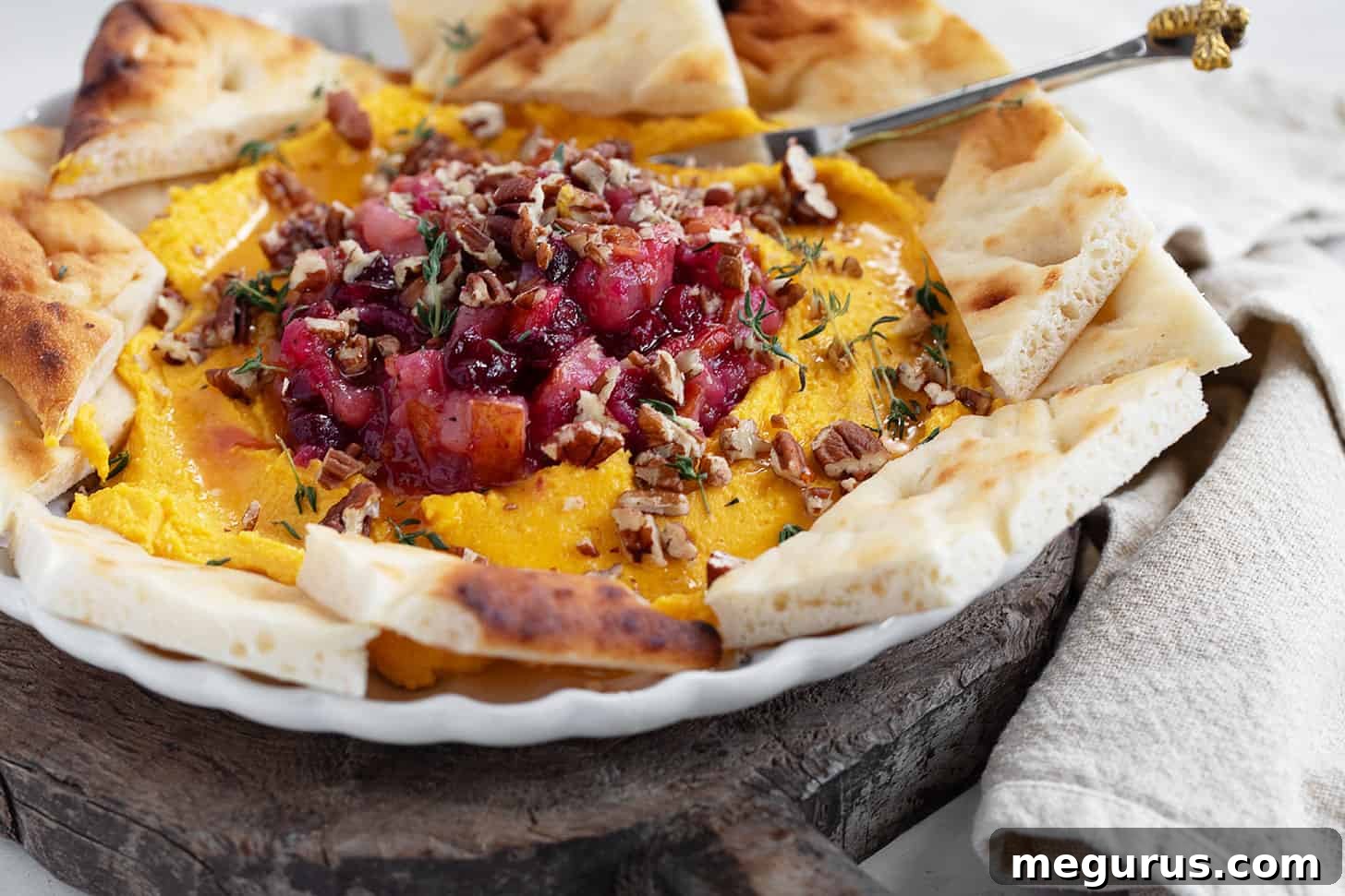 Butternut squash whipped feta on a festive serving plate, adorned with chutney, pecans, and thyme.