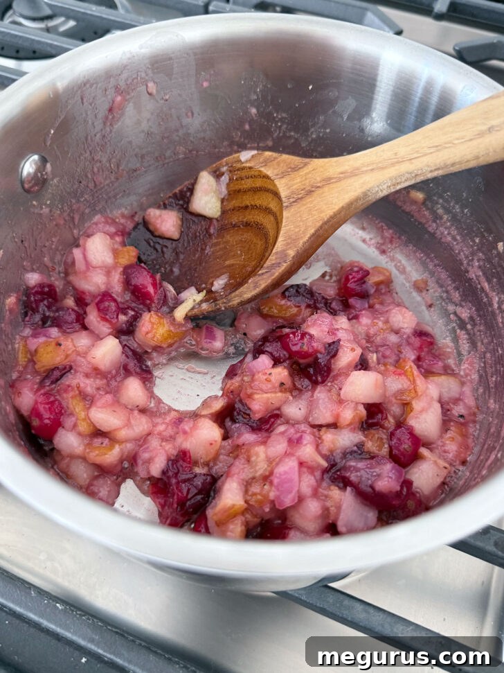 Pear and cranberry chutney after simmering, showing softened fruit.