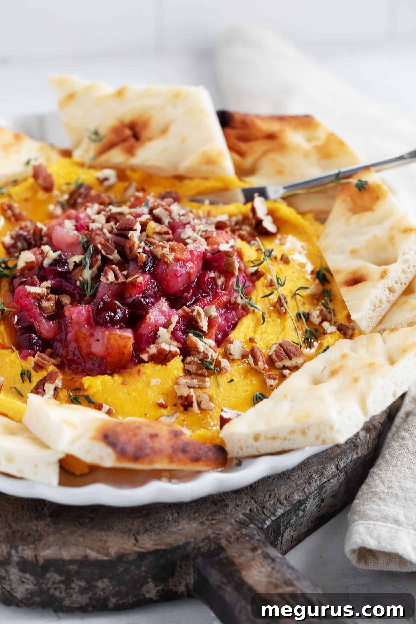 An overhead shot of Butternut Squash Whipped Feta, artfully arranged with chutney, nuts, and fresh herbs.