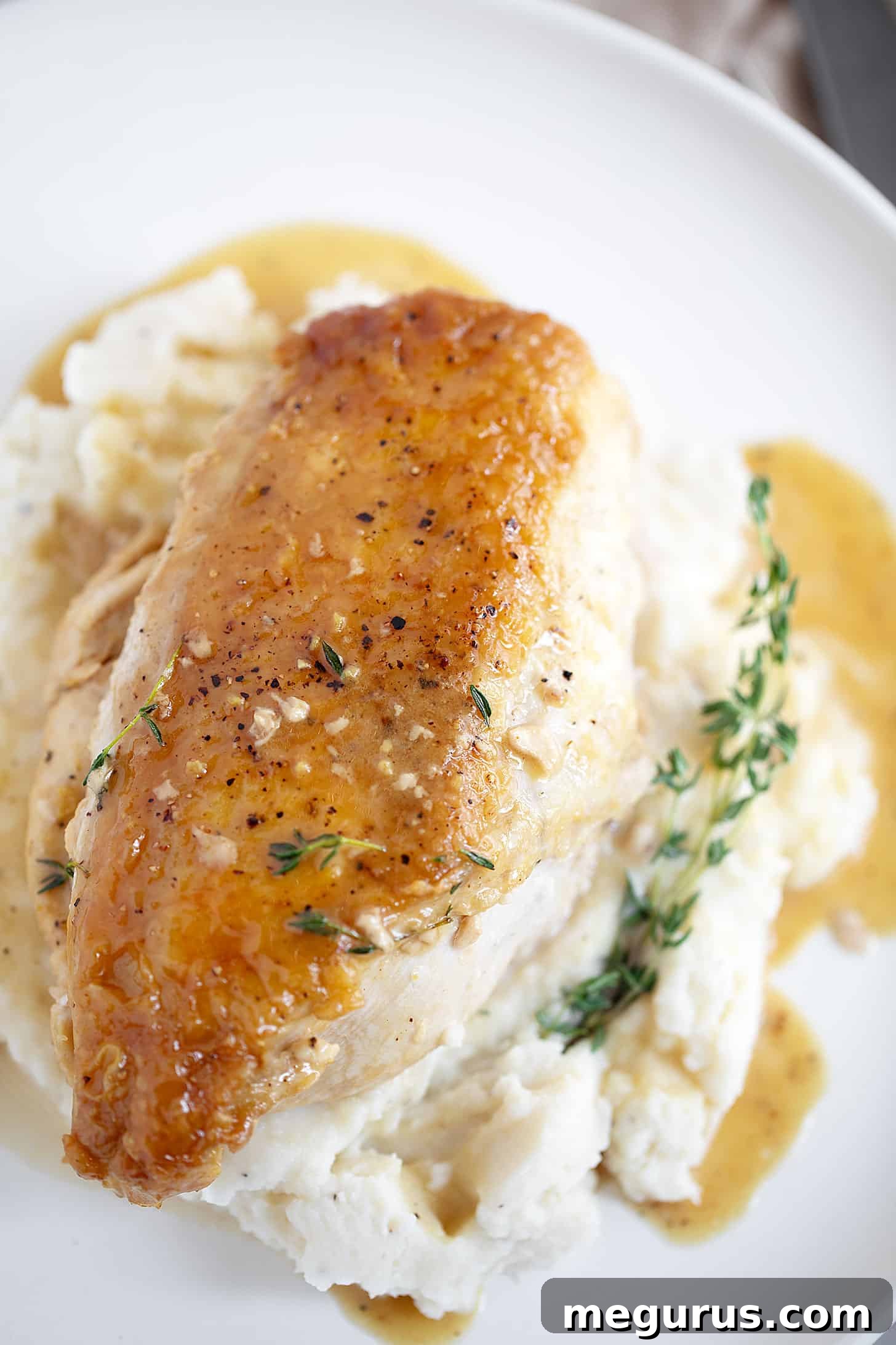 Maple mustard chicken breasts on mashed potatoes, garnished with fresh herbs, ready to be served.