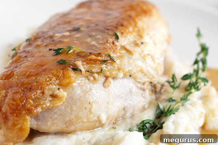 Close-up of a maple mustard glazed chicken breast, showcasing its crispy skin and rich sauce.