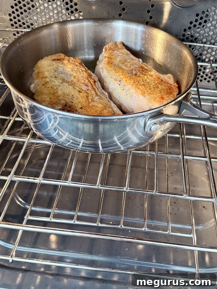 Transferring the skillet with seared chicken to the oven to complete cooking.