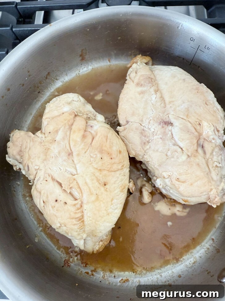 Flipping the chicken breasts skin-side down into the simmering maple mustard glaze.