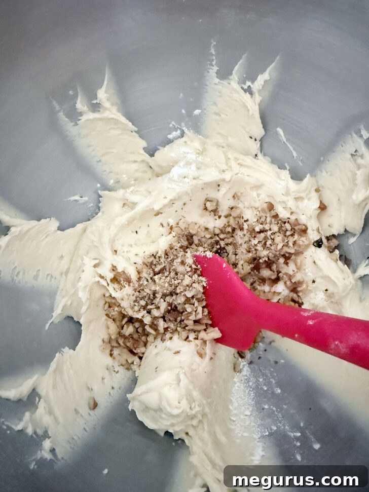 Chopped walnuts are being gently folded into the loaf batter in a mixing bowl.