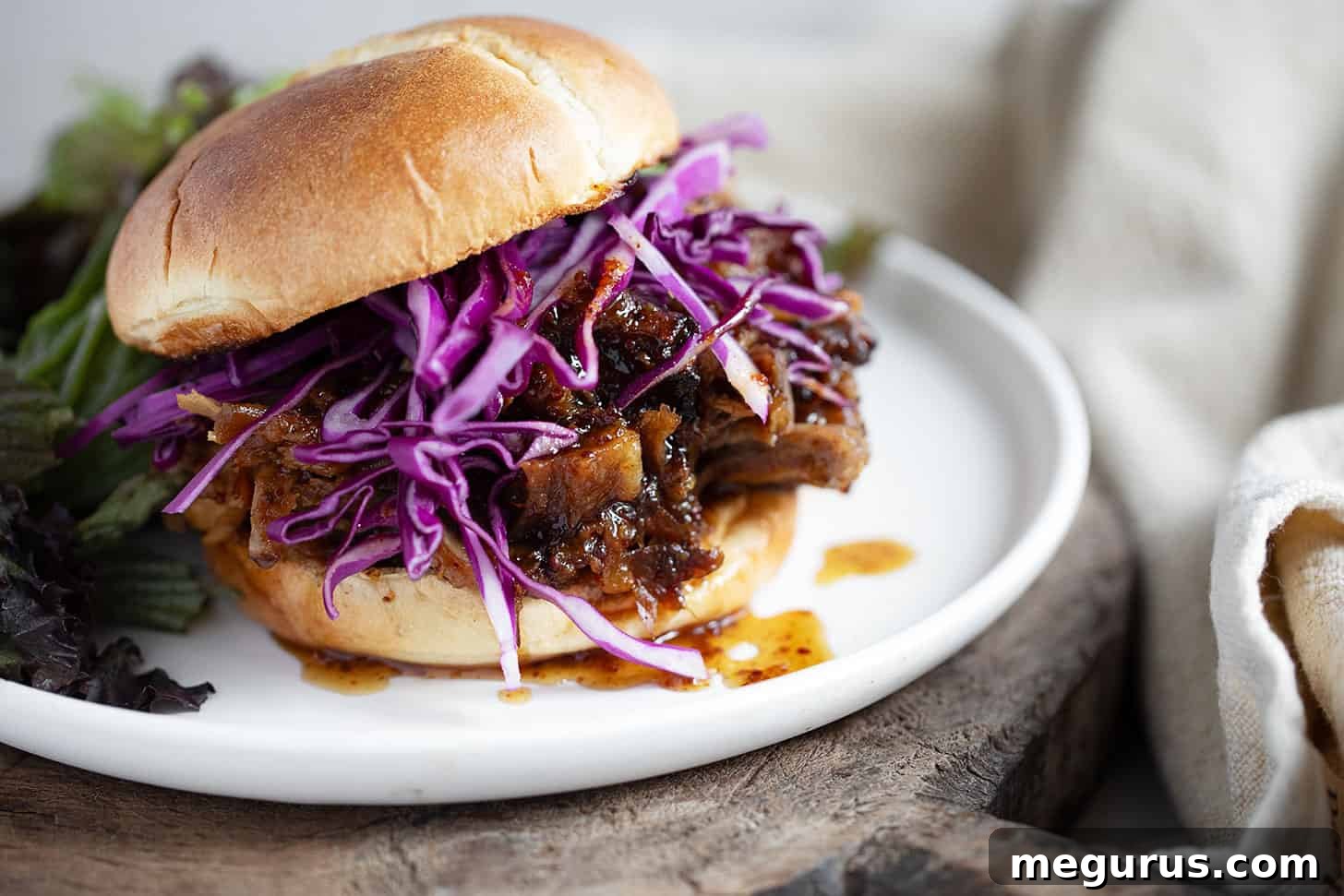 Delicious mustard maple pulled pork served on a soft bun with a generous helping of shredded cabbage, ready to be enjoyed.