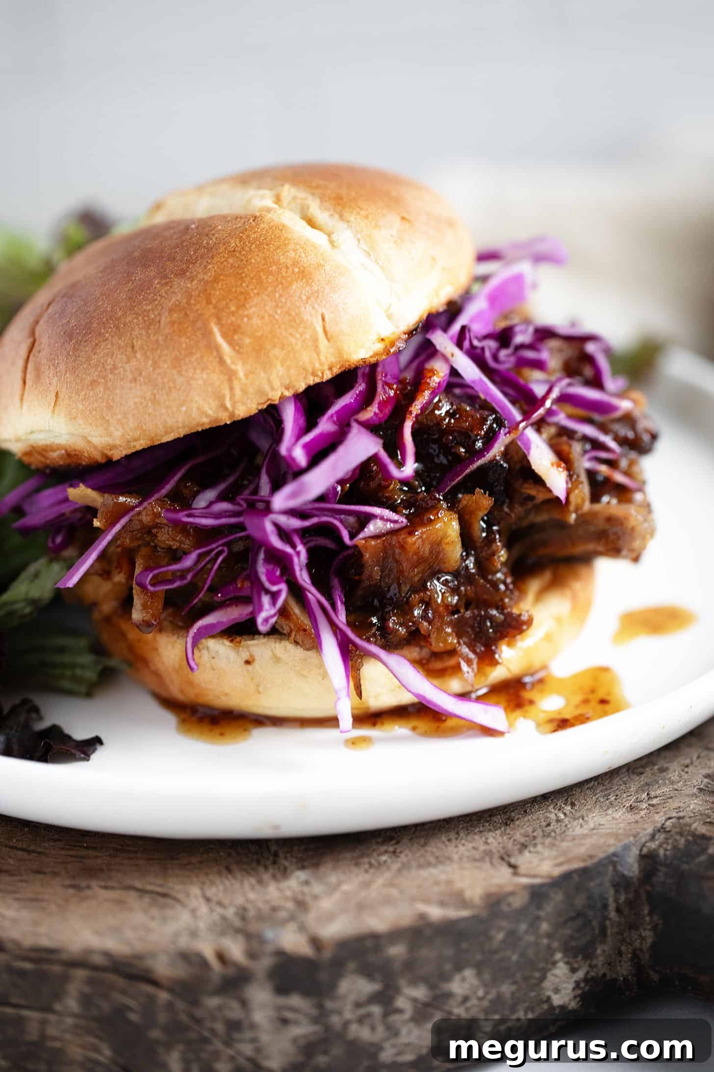 Mouthwatering mustard and maple pulled pork piled high on a bun, garnished with vibrant red cabbage for crunch and color.