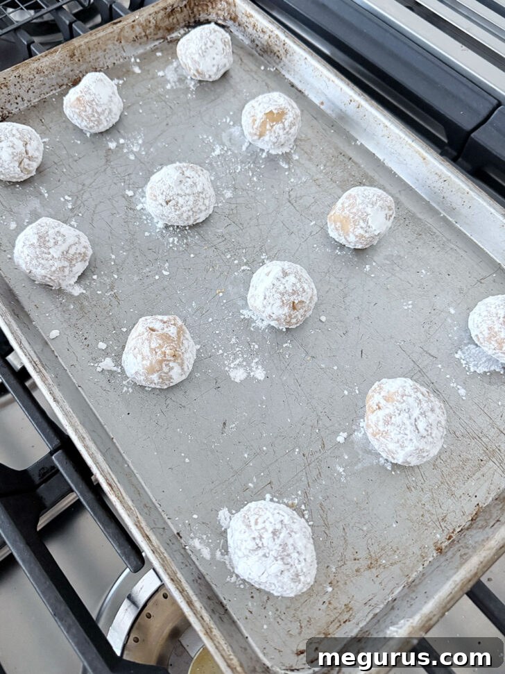 Sugared cookie dough balls spaced out on an ungreased baking sheet, ready for the oven.