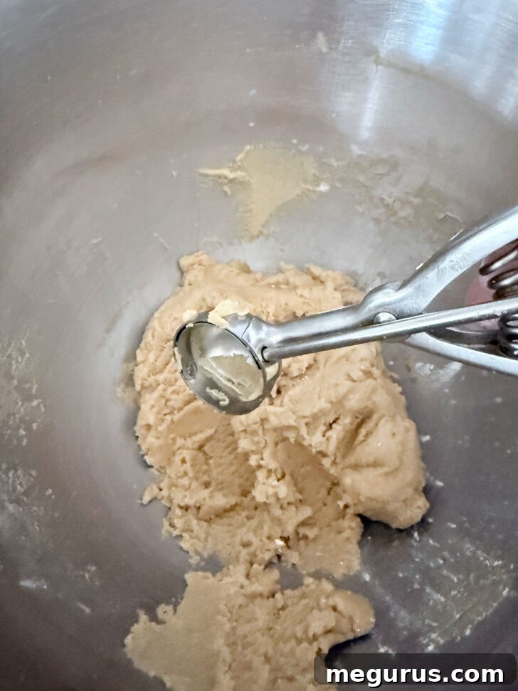 A cookie scoop being used to portion out chilled cookie dough.