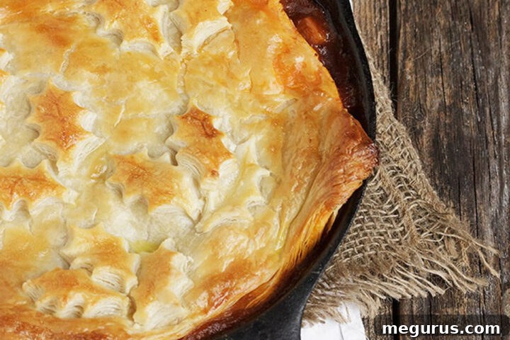 beef and vegetable pot pie with puff pastry crust in cast iron skillet