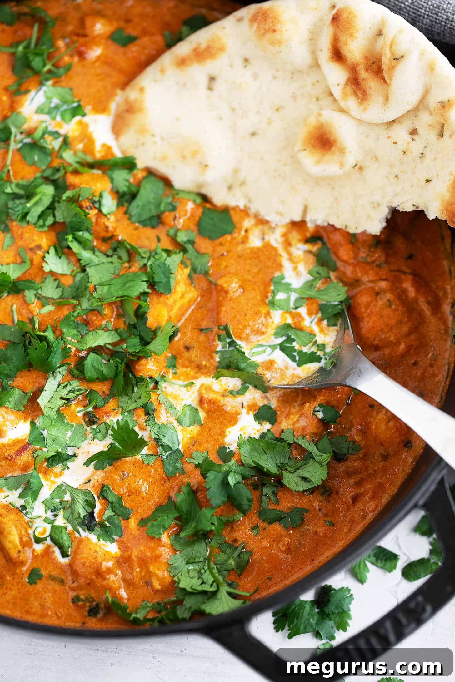 Butter chicken in skillet with naan.