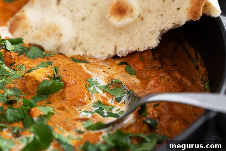 Butter chicken in a skillet with naan bread.