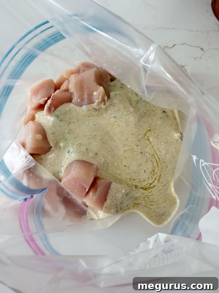Cubed chicken with butter chicken marinade in a plastic zipper bag.