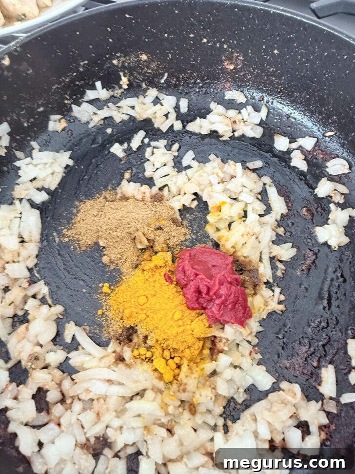 Adding the butter chicken spices to the onions in the skillet.