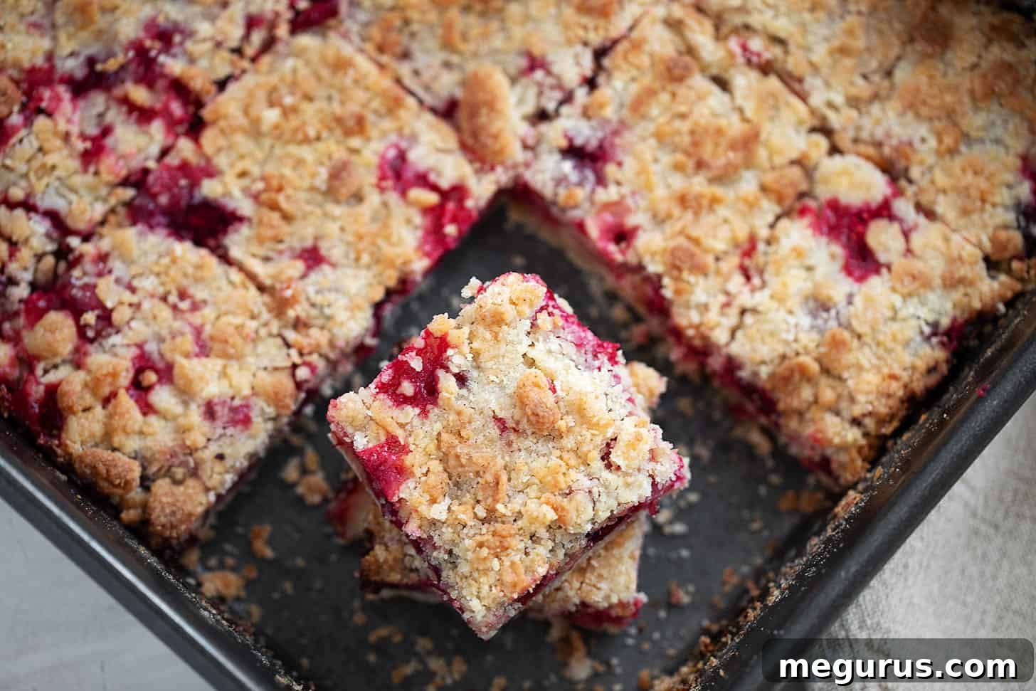 Beautifully cut Cranberry Crumb Bars in a baking pan, showcasing the golden crumb topping and ruby-red cranberry filling.