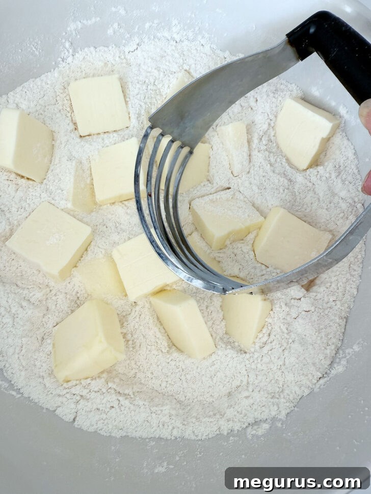 Cold butter pieces being added to a bowl of dry ingredients for the crumb mixture.