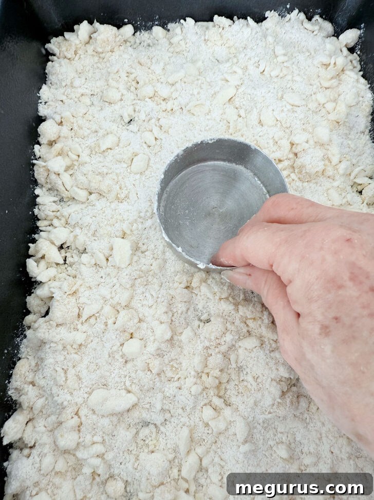 Pressing a portion of the crumb mixture firmly into the bottom of a baking pan.
