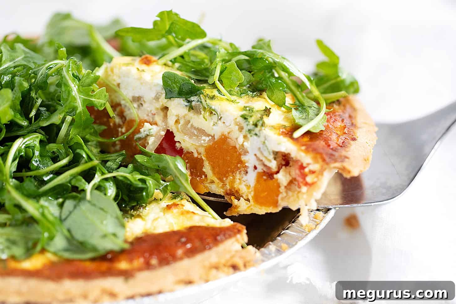 A perfectly sliced butternut squash quiche, revealing its creamy filling and tender vegetables, ready to be served.
